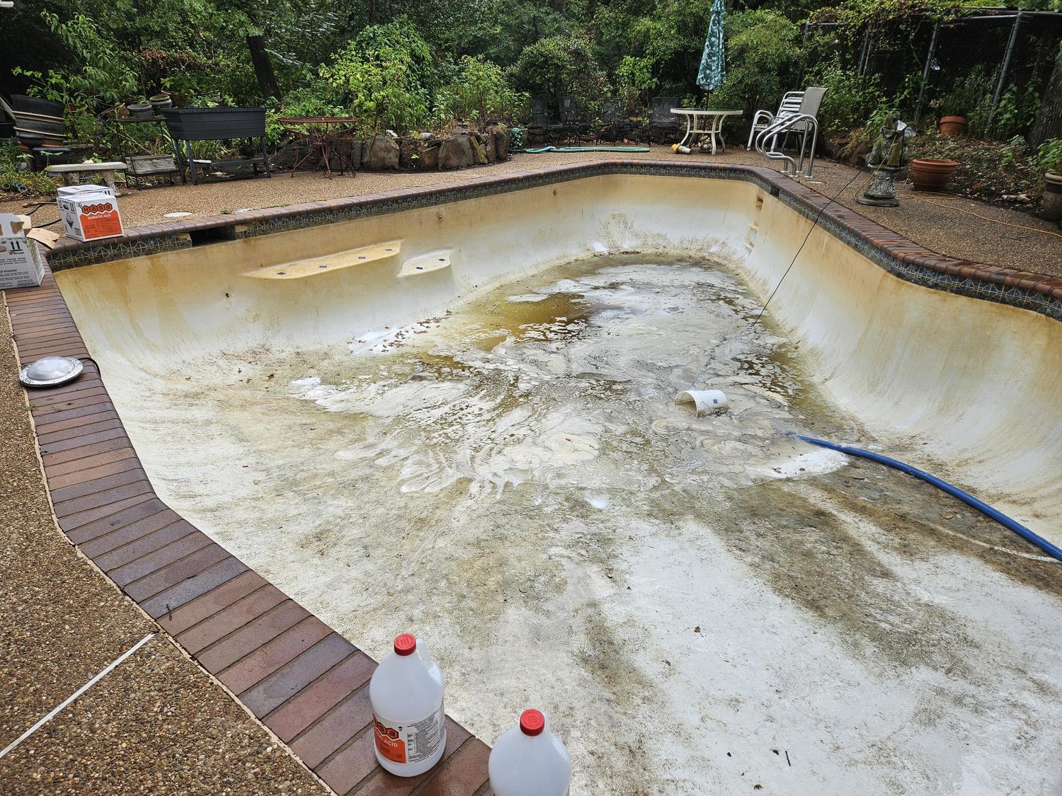 Drained Mansfield pool before cleaning, plaster stained brown and yellow across the floor