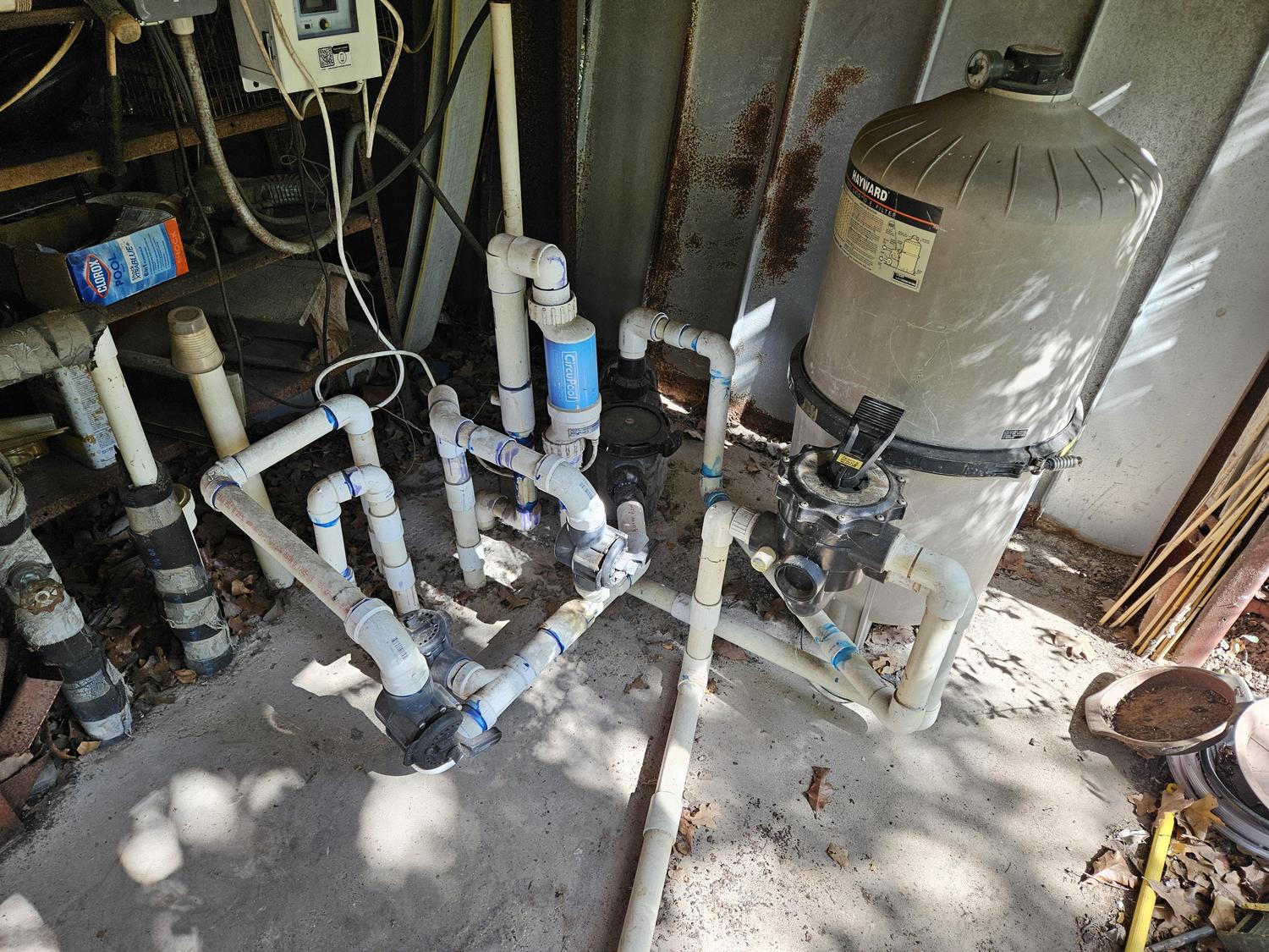 Old pool equipment pad plumbing in Mansfield, dull grey PVC and worn valves before replacement
